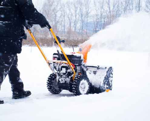 Side view of a man removing snow using a machine