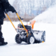 Side view of a man removing snow using a machine